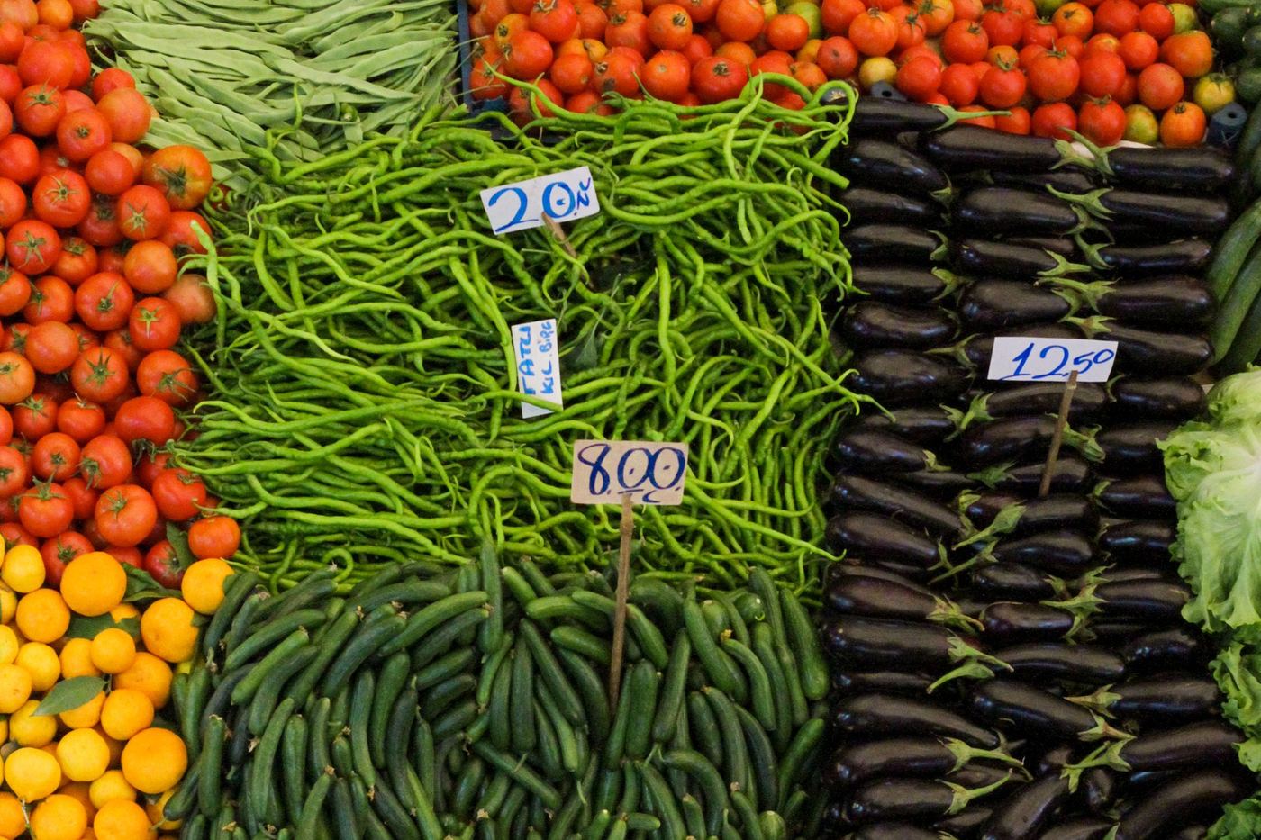 A market stall piled with tomatoes, green beans, courgettes and aubergines